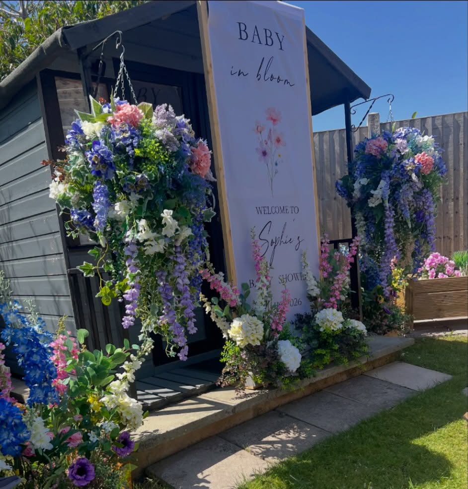 Blue, pink and white flowers surrounding a baby shower welcome sign