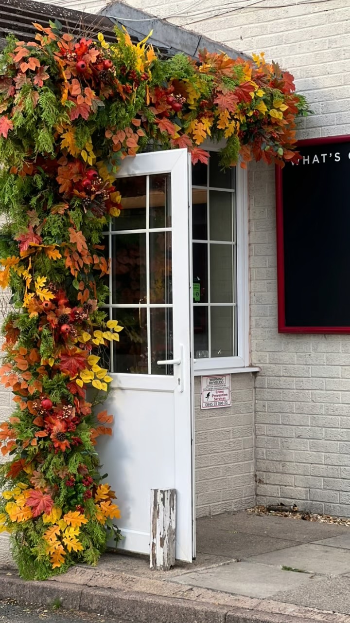Large autumn foliage installation framing a white business entrance