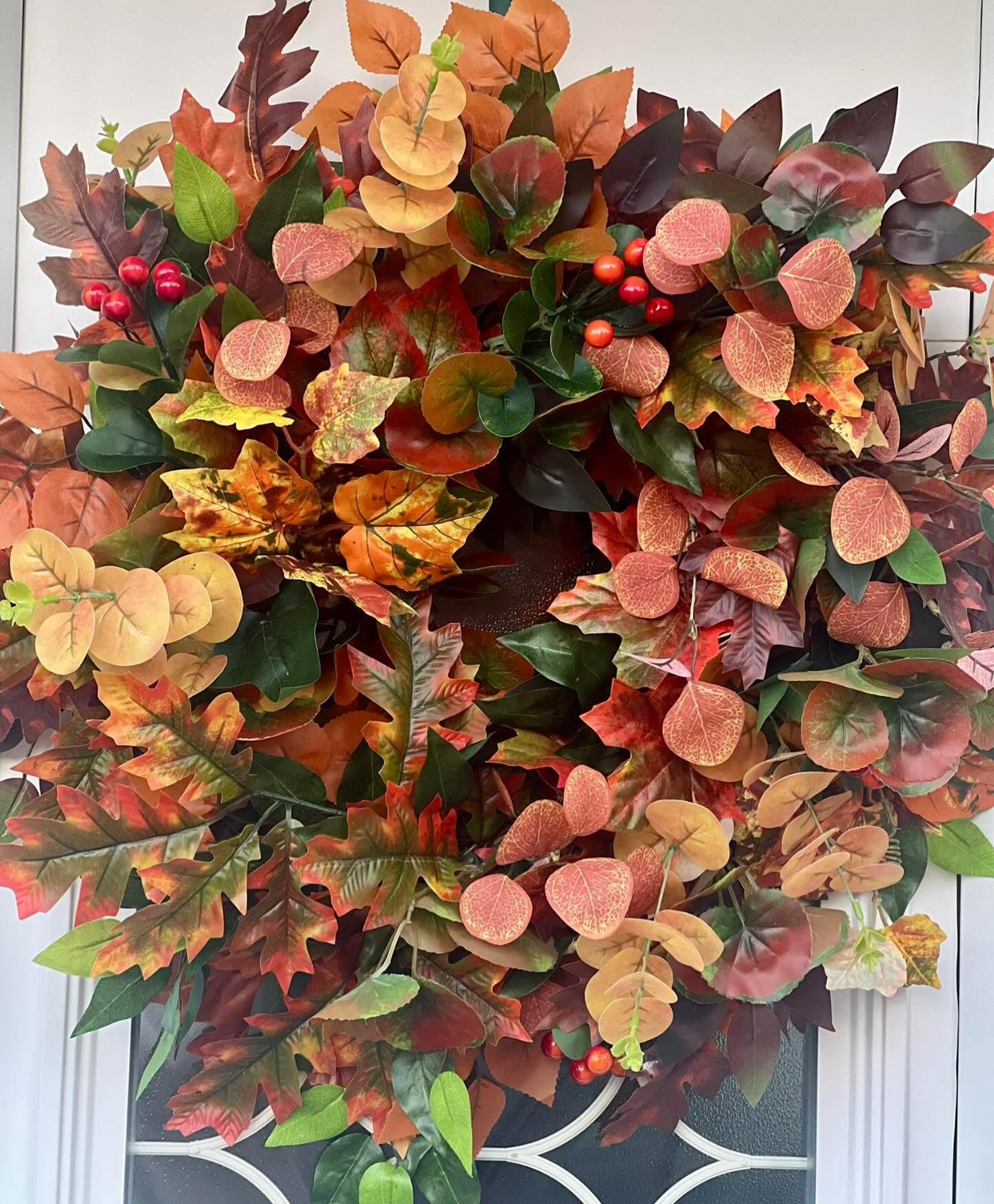 Full autumn wreath layered with red, orange and green foliage