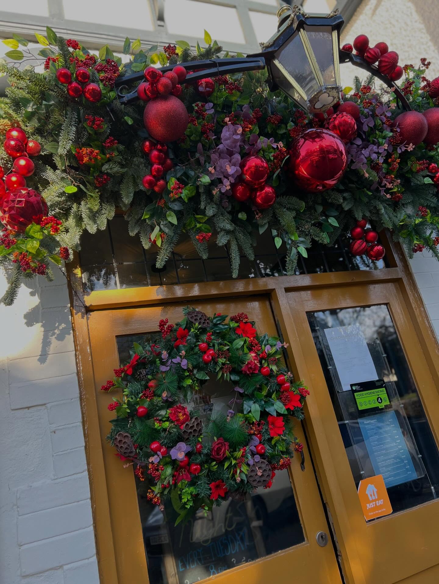 Christmas greenery, red baubles and a wreath dressing a shop doorway