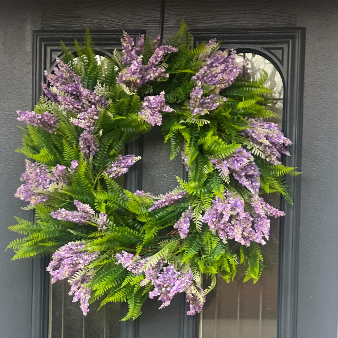 Lavender and fern wreath displayed on a dark front door